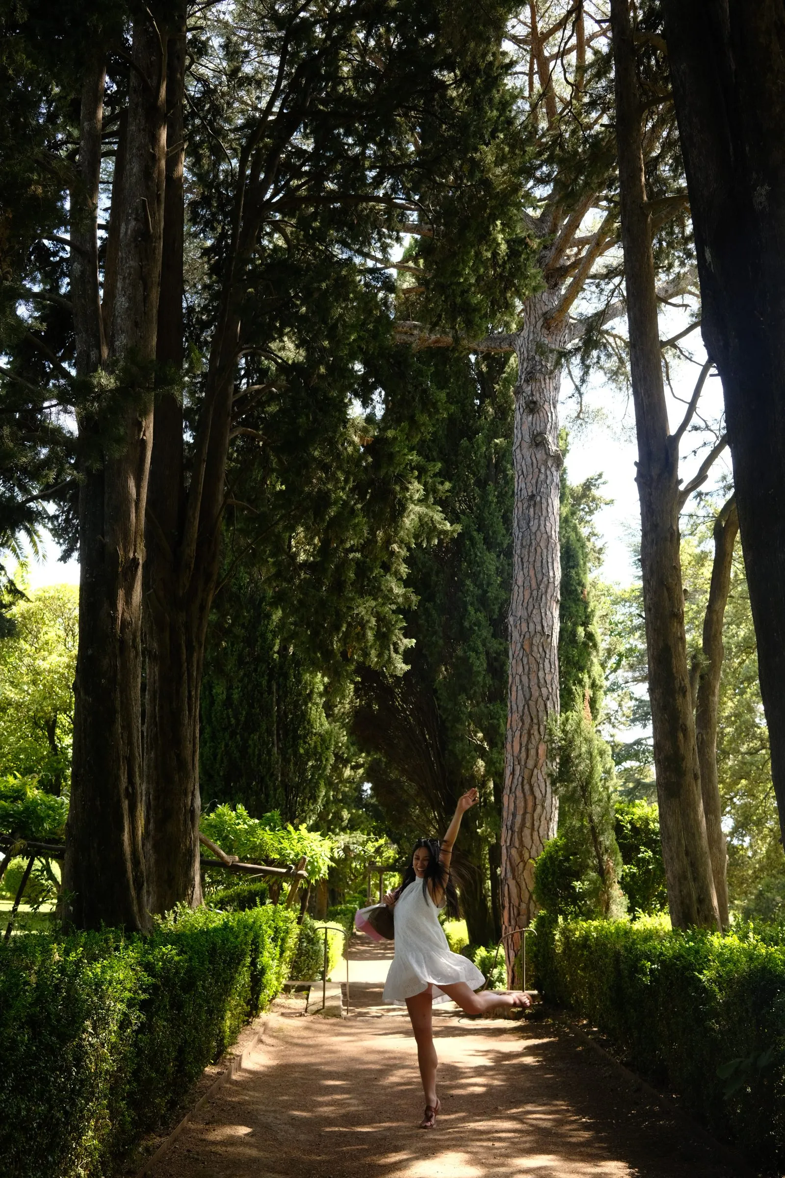 Gab Ybiernas mid-leap on a tree-lined path, white dress catching the sun